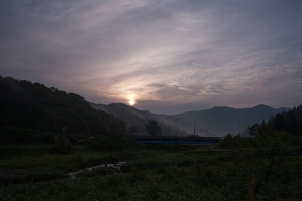 雲と山の稜線との間の朝日の出。