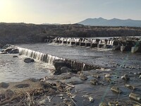 岸辺から見えた川の堰と山並み
