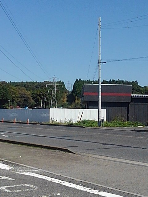 道路の向こうの案山子みたいな鉄塔